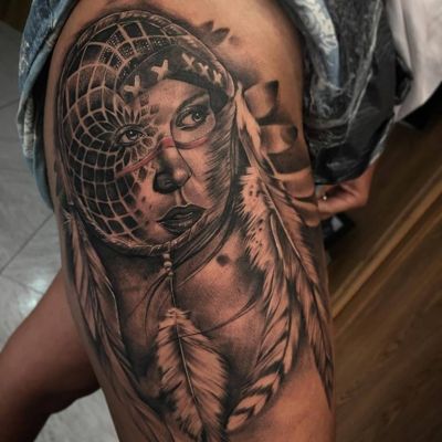  Tatouage attrape rêve avec un visage en son centre sur le haut de la cuisse